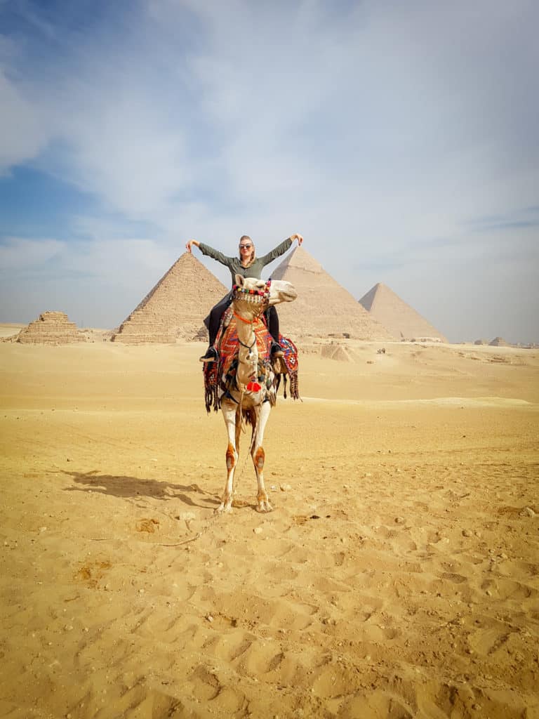 Cheesy tourist post in front of Pyramids of Giza on camel back
