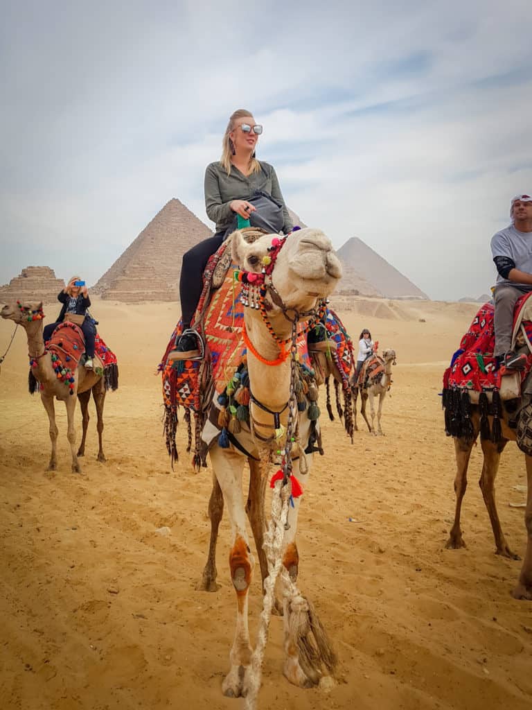 Riding camels past pyramids of Giza