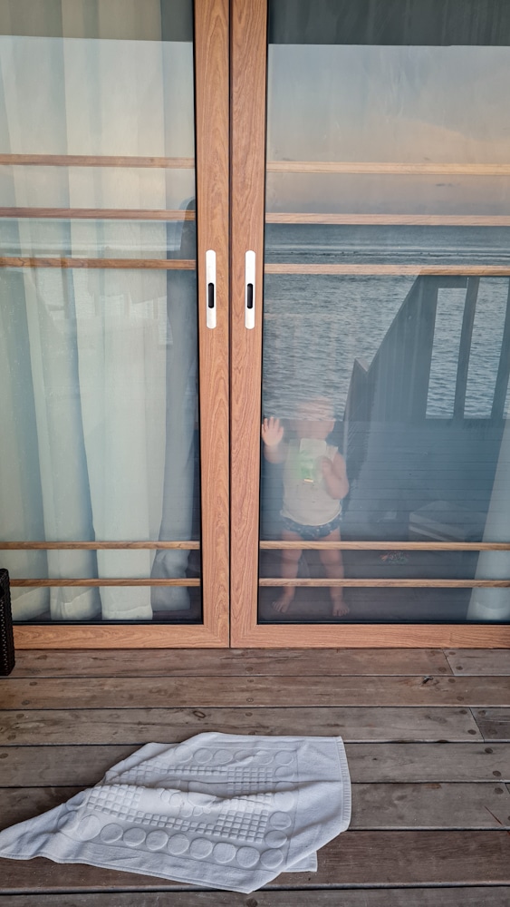 Baby standing at door of water villa