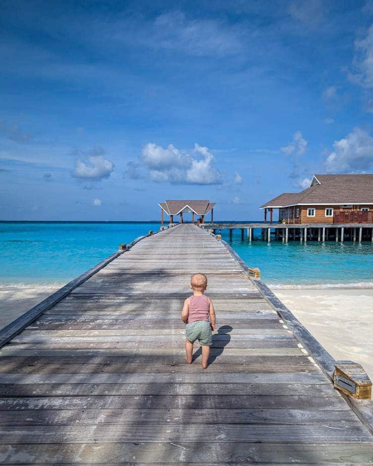 Baby walking along pier in the Maldives